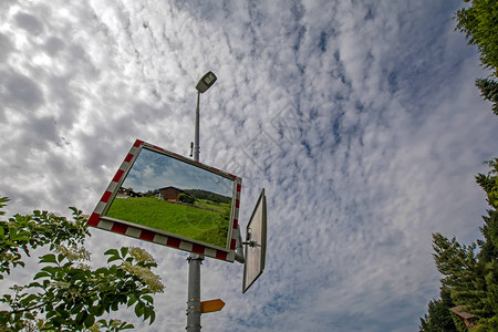 街道上安全道路交通镜的低视角与多云的天空映衬着木制传统小屋瑞图片