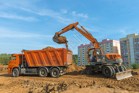 现代挖掘机在施工现场进行挖掘工作挖掘机正在装载挖掘到卡车液压挖掘机是重型施工设备背景图片