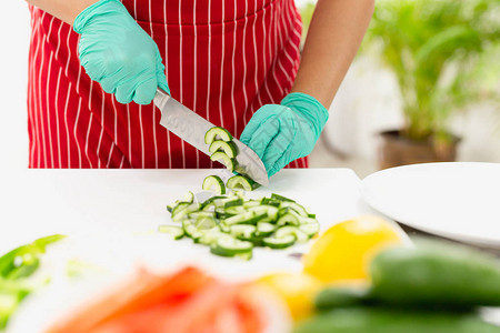 厨房里有绿手套切黄瓜的女人图片