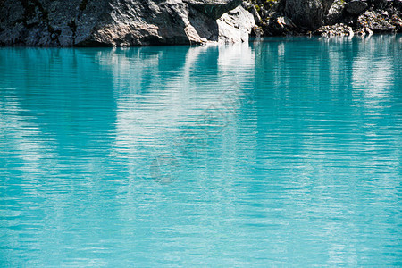 蓝色大海岸边的岩石绿松石山湖河面背景图片