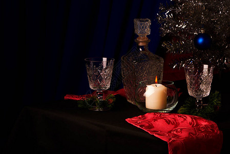 新年静物玻璃和透明玻璃的滗水器节日盛宴桌子是用黑布铺的兴粉红色背景图片