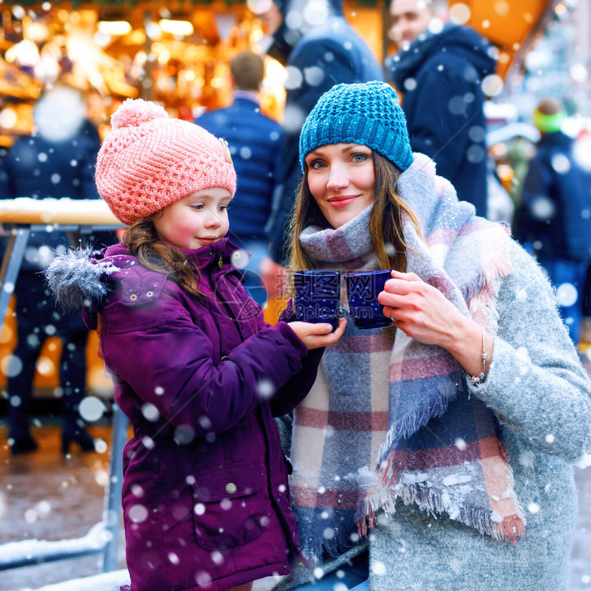 小可爱的女儿和母亲端着一杯热气腾的热巧克力或儿童拳快乐的儿童女孩和美丽的女人在德国的圣诞市场上圣诞节家图片