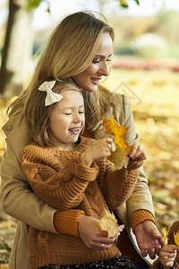 秋天时节采摘叶子的母女图片