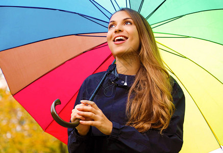 在秋天的季节关闭彩虹伞下微笑的女孩图片