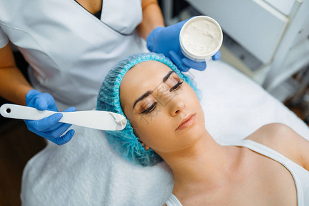 美容师将乳霜涂抹在女患者的脸上图片