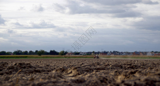 农民用一台旧拖拉机在背景中耕作旱地农业干旱土壤耕作农业和农业村景图片