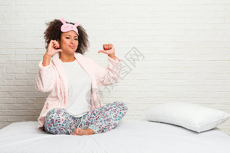玛琪雅朵穿着皮雅玛穿衣躺在床上的年轻非洲女感到自豪和自信背景