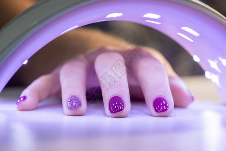 在紫外线灯下用凝胶清漆来烘干指甲图片