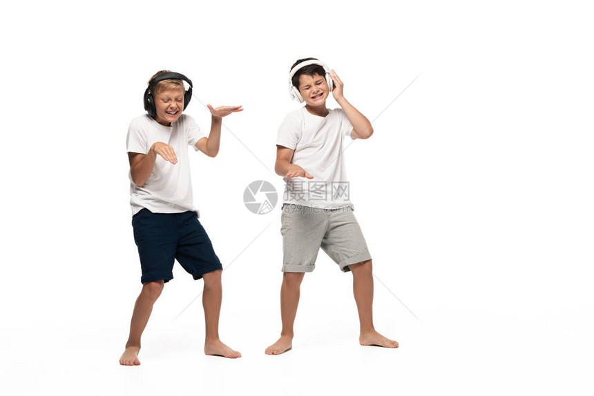 两个快乐的兄弟用耳机听音乐和在白人背景图片