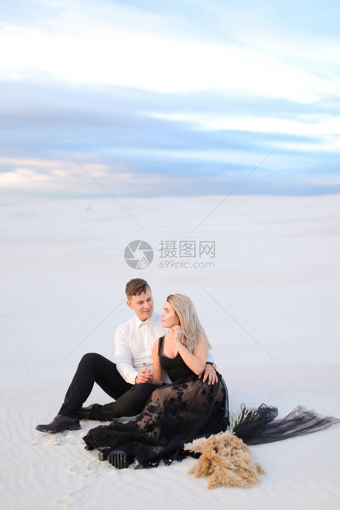 身着黑衣服的年轻女和坐在雪上的男人在草原上图片