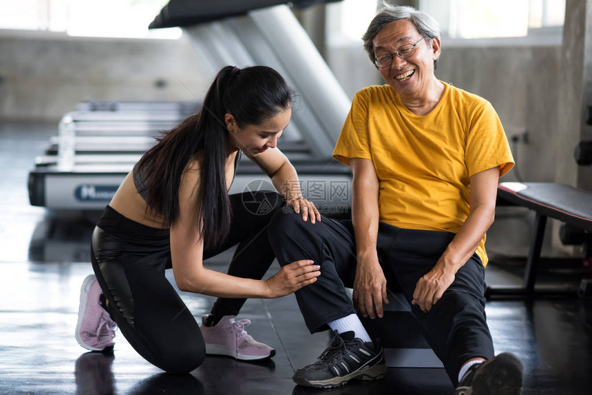 快乐的老人在运动后得到美丽的亚洲女人的腿部按摩图片