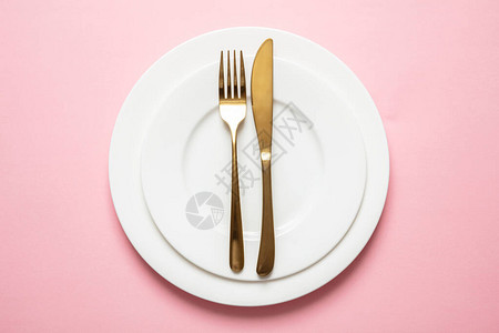 黄金和粉红色奢华桌设置金餐具和粉红背景的白色盘子顶视图片