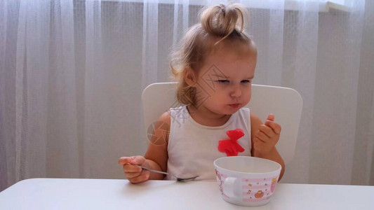 婴儿女孩在白色背景的小儿童桌上吃婴儿食品儿童图片