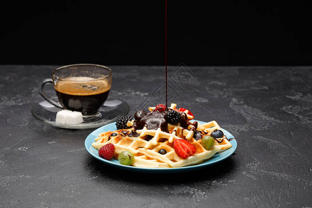 一杯加糖的黑咖啡和维也纳华夫饼草莓覆盆子醋栗和巧克力在空荡的黑色图片
