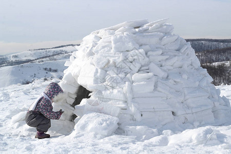 孩子拿着雪球蹲在爱斯基摩人的家图片