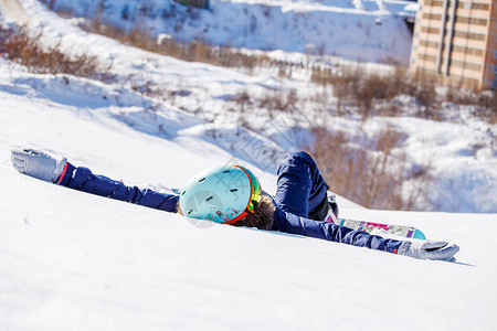 白天在雪坡上躺着雪板的运动女图片