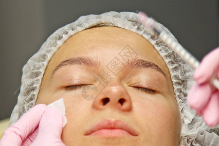 一位美容学家将肉毒素注射到女脸上的皱纹上高清图片