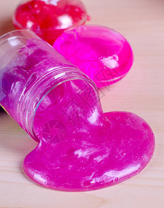 从瓶子上洒出明亮的粉红色黏液在一张桌子上粘着闪光图片