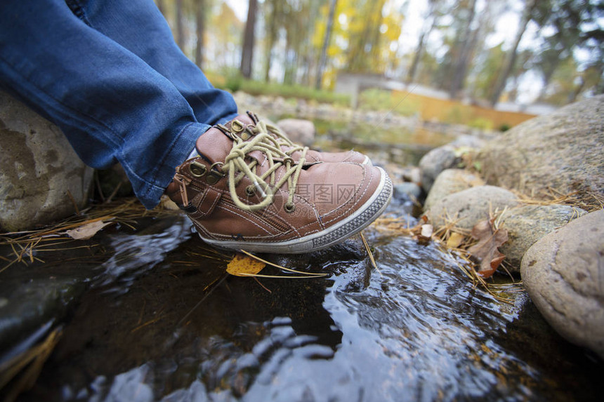皮鞋上脚印着自然背景的皮鞋瀑布上的儿童鞋旅图片