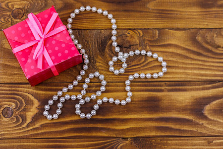 木制背景中的礼品盒和珍珠项链图片