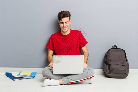 青年学生男子坐在他家的地板上手图片