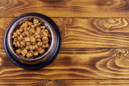 木地板上金属碗中的猫或狗罐头食品顶视图图片