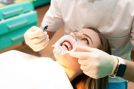 检查过程中有脸颊擦拭器的病人在牙科椅上图片