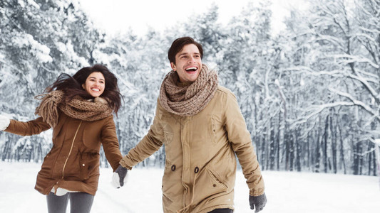 圣诞早晨在雪林中快乐的一对夫妇携手共图片