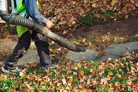 在公园里使用吹叶机清洁道路的人秋天的季节公园清洁服务秋天图片