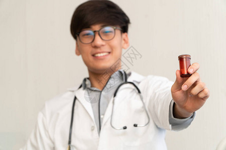 带着听诊器和制服的亚洲医生拿着药瓶图片