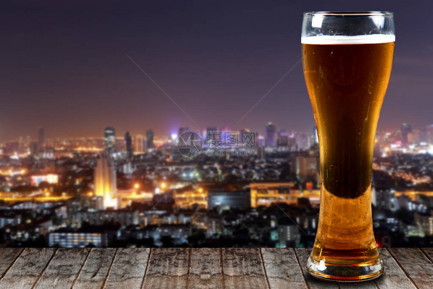 在夜间背景下的木制城市上喝杯啤酒图片