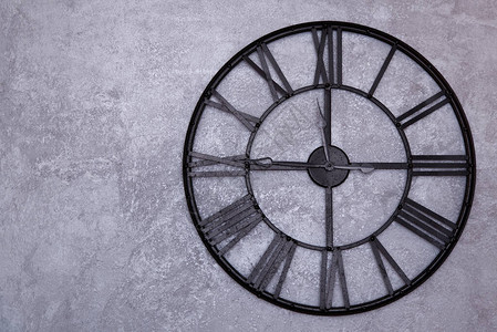 墙上有罗马数字的老式挂钟灰色的灰泥墙时钟显示一刻钟到十二点图片