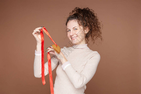 卷发的欧洲女向镜头展示手工制作的心形新鲜姜饼图片