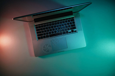 桌边和夜幕背景的彩色光线下美丽的银笔记本电脑图片