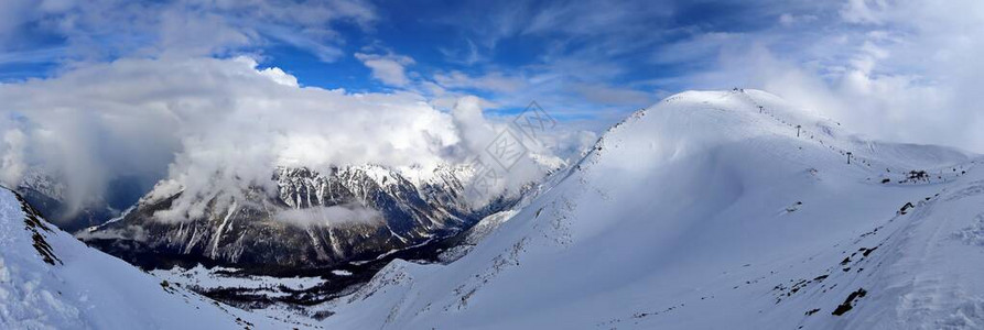 在云彩蓝天的雪山峰顶全景图片