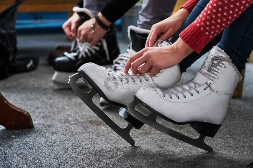 准备滑冰的年轻夫妇他们的手系冰球溜冰鞋图片