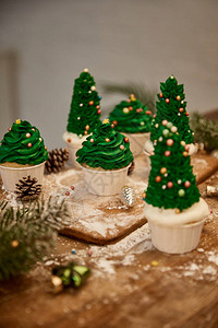 装饰圣诞树纸杯蛋糕有圣诞节球餐桌上有图片