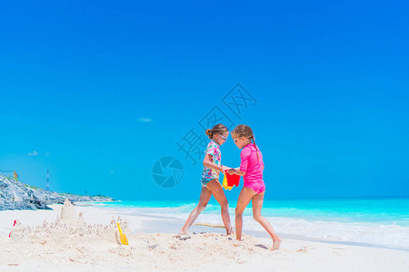 小女孩在热带海滩玩沙滩玩具很开心暑假期间海滩的图片