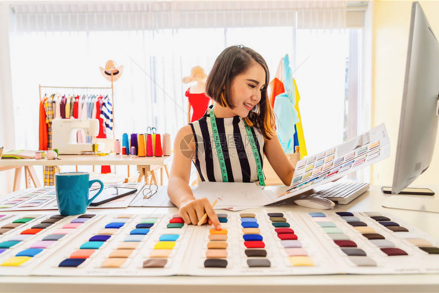 年轻的亚洲设计师女在工作场所使用电脑并选择多色图表小型企业创企业主企业家现代自由职业生活方式概图片