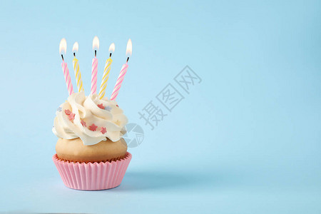 生日纸杯蛋糕蜡烛放在浅蓝色背景图片