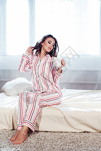 穿着睡衣的女孩早上醒来坐在床上喝咖啡背景图片