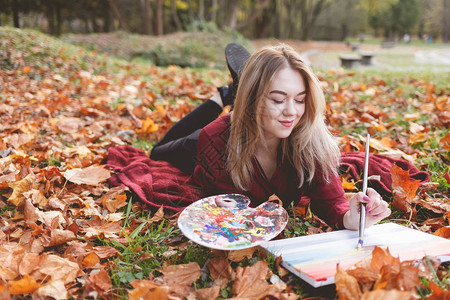 年轻女艺术家在公园里放松着她最喜爱的好女孩画一幅画图片