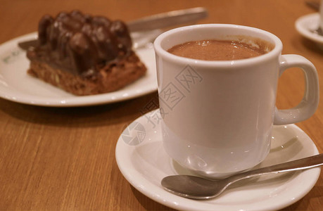 一杯热巧克力和一盘模糊的巧克力蛋糕放图片