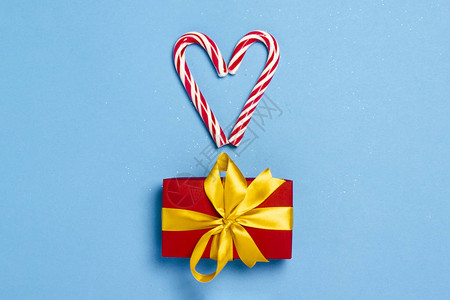 糖果焦糖甘蔗以心脏和蓝色背景上的礼品盒的形式图片