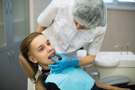女牙医在牙科办公室为病人配备口腔保护可移动的矫形牙配对和矫正教练器械图片