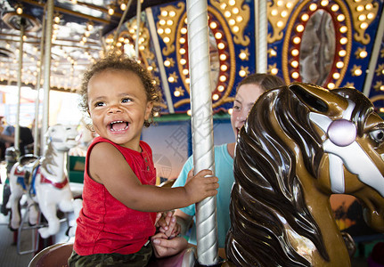 加州迪士尼乐园可爱的混血小男孩在有趣的嘉年华旋转木马上享受骑行一个快乐的男孩在夏日嘉年华上微笑着骑旋转背景
