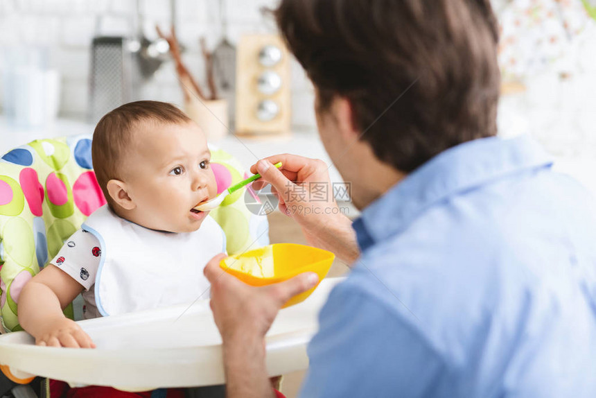 首先营养父亲在厨房里喂养他好奇的宝图片
