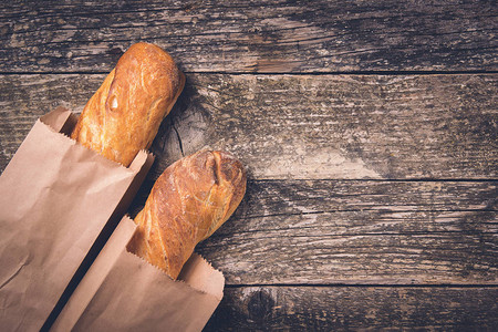木制背景纸袋中的新鲜法式长棍面包图片