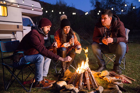露营者在营地的火和啤酒周围一起放松图片
