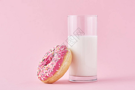 粉红色背景上加杯牛奶的甜圈图片